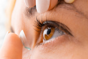 Close-up van een vrouw die een contactlens inzet