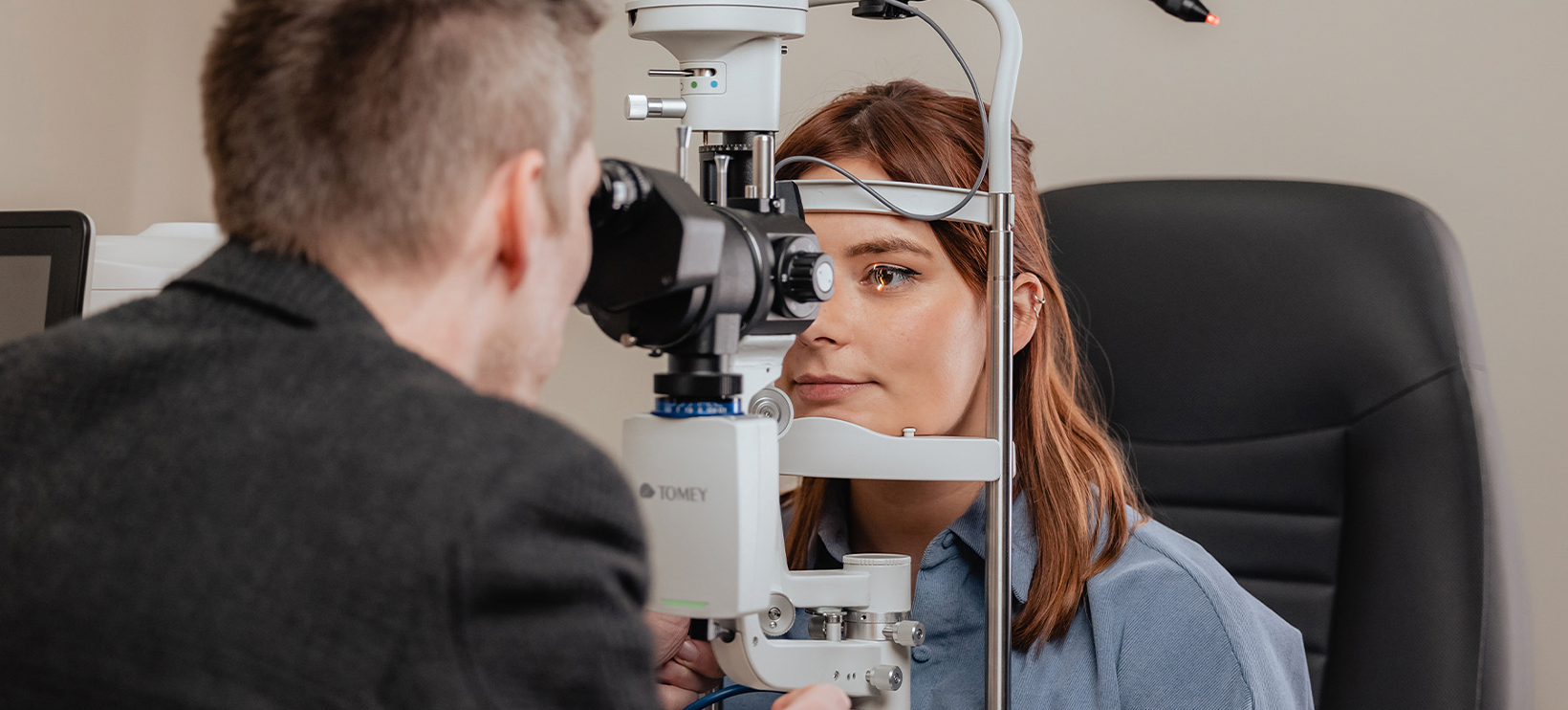 Vrouw ondergaat een oogonderzoek met een spleetlamp terwijl de opticien haar oog nauwkeurig bekijkt.